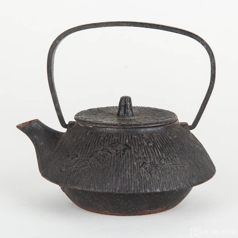 日本南部铁器《旧制铁壶》1件，整体形态为樱花制式，壶身呈古朴纹饰，壶嘴下方印有字样		
